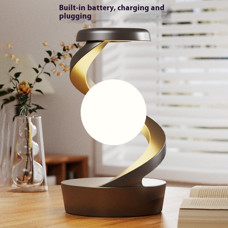 Lunar Levitation magnetic floating moon lamp rotating above its base with a warm glow in a dark room - view 2 of 3