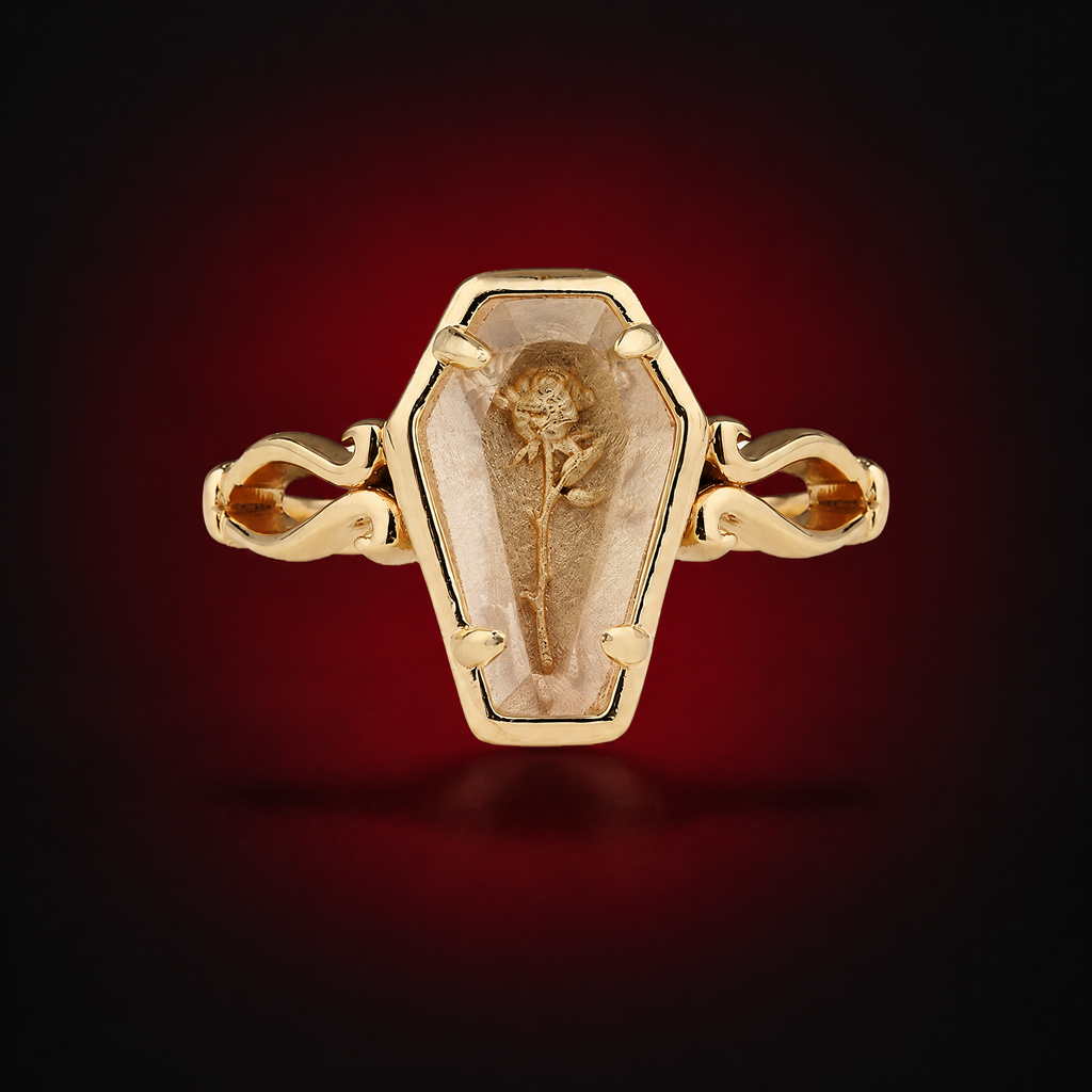 Selected Gold Thorned Rose Coffin Ring against a dark crimson background, showing the coffin-shaped face and rose motif
