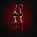 Pair of selected 1 Style crimson coffin cross earrings against a dark crimson background