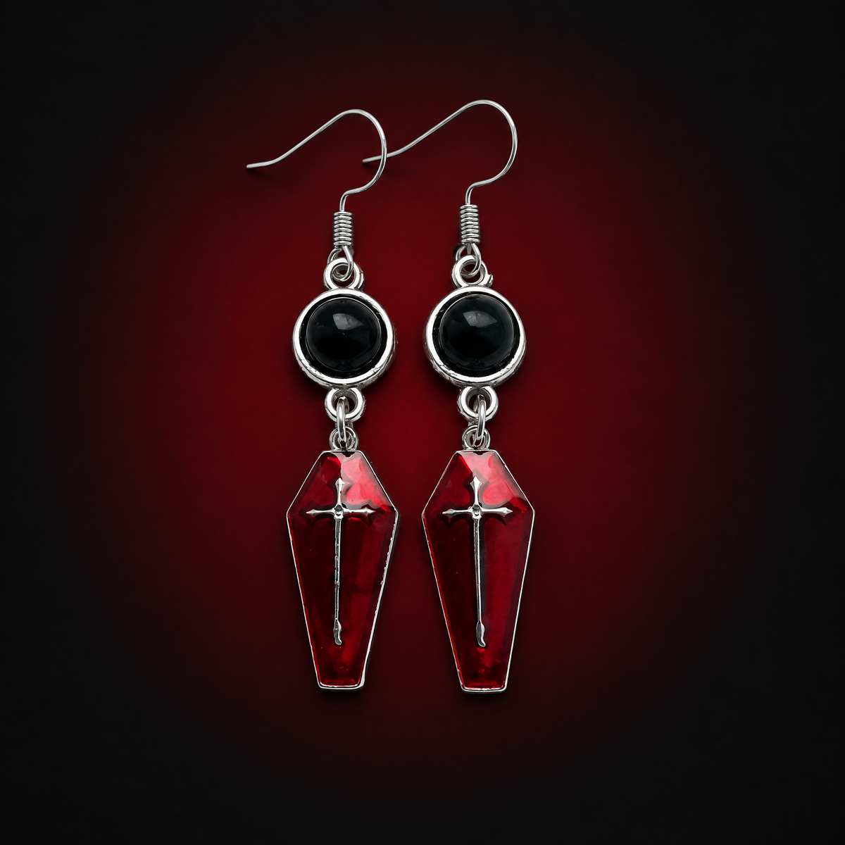 Pair of selected 1 Style crimson coffin cross earrings against a dark crimson background