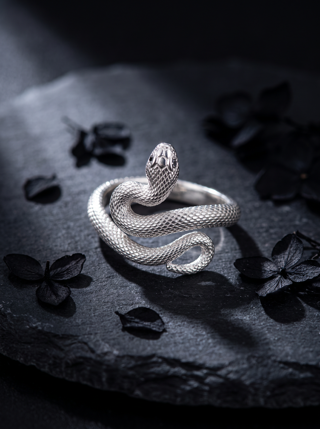 Serpent's Coil silver rattlesnake ring macro on dark slate with black petals